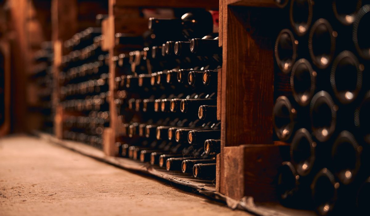 Storage room with glass bottles of alcoholic drink in wooden racks